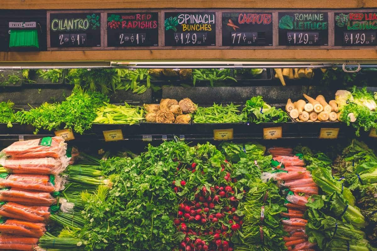 Grocery store shelves full of fresh vegetables, an important part of a vegan food list for beginners